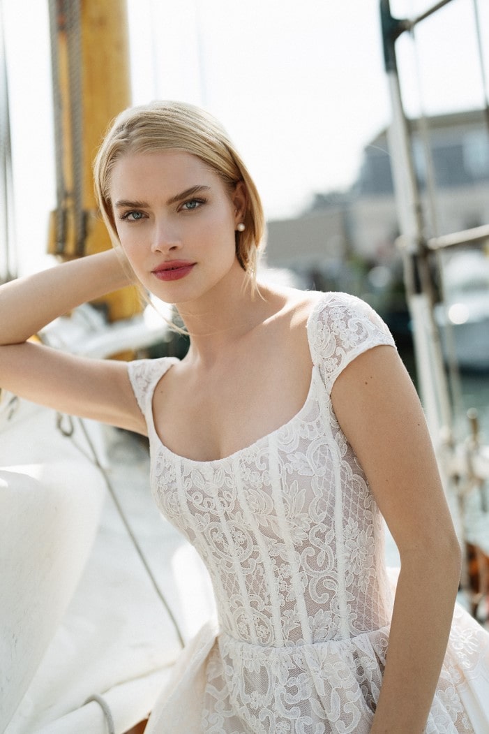 Close up of model wearing lace cap sleeve wedding dress with corset